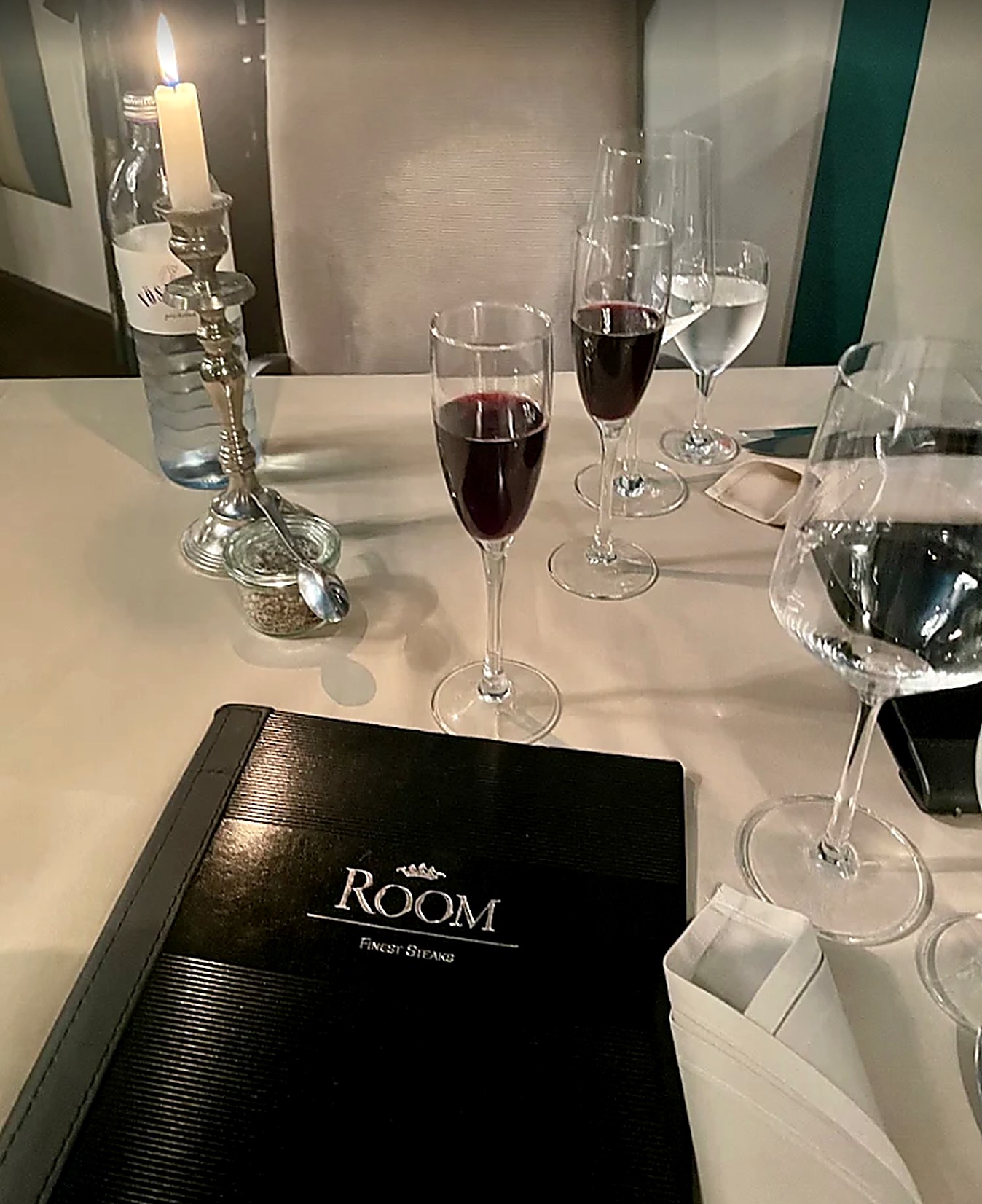 Gedeckter Tisch im ROOM mit Kerze, Rotwein und Menübuch